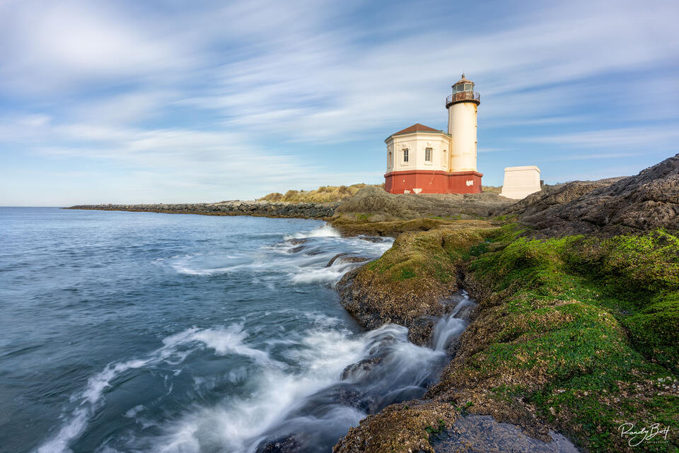 Coquille river lighthouse at sunrise during a long exposure photograph streaking the clouds.