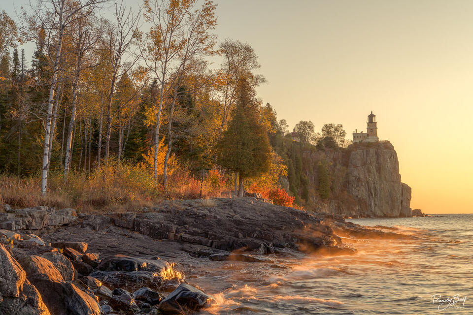 Split Rock Lighthouse on the shore of Lake Superior catching the gold light of the rising sun.
